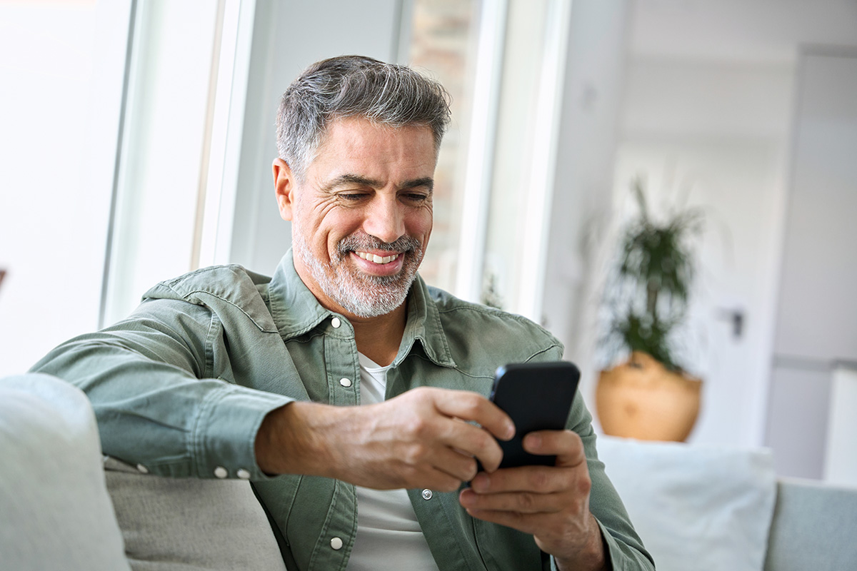 image of man sitting at home with mobile in his hand
