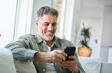 image of man sitting at home with mobile in his hand