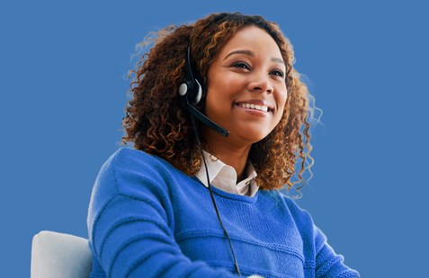 Woman smiling with headset wearing a blue jumper, on blue blackground