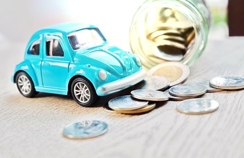 Blue car toy over a jar of coins