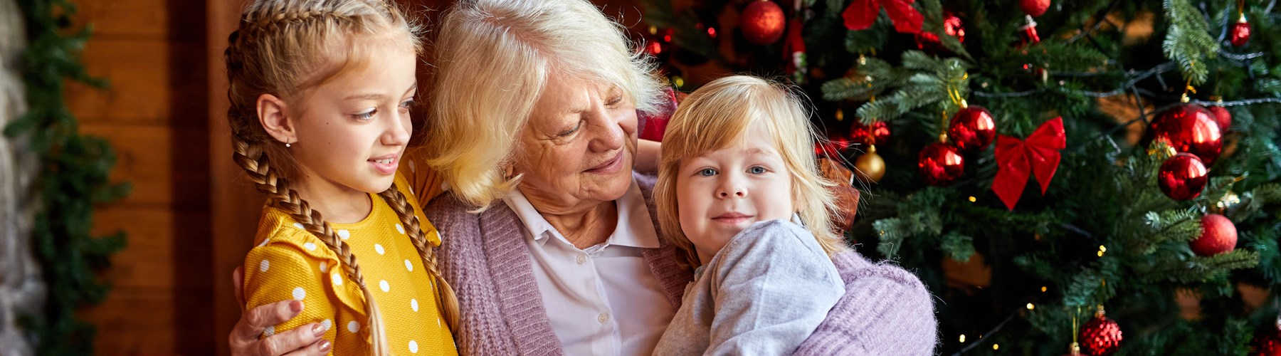 Grandmother with her grandchildren in front of the christmas tree