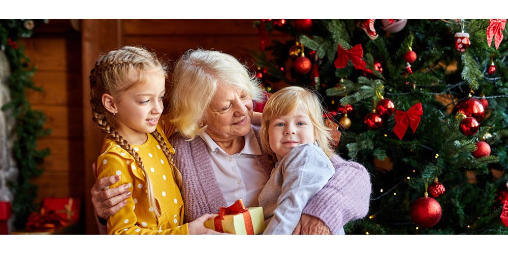 Grandmother with her grandchildren in front of the christmas tree