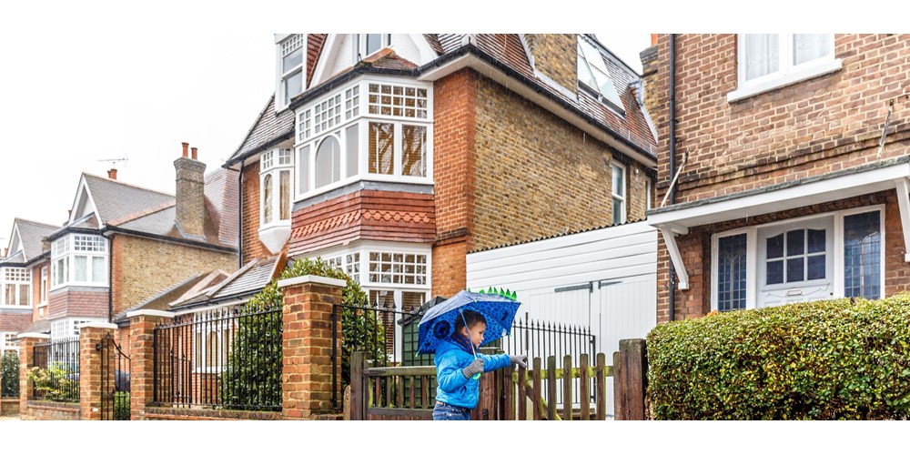Kid with an umbrella going into his home