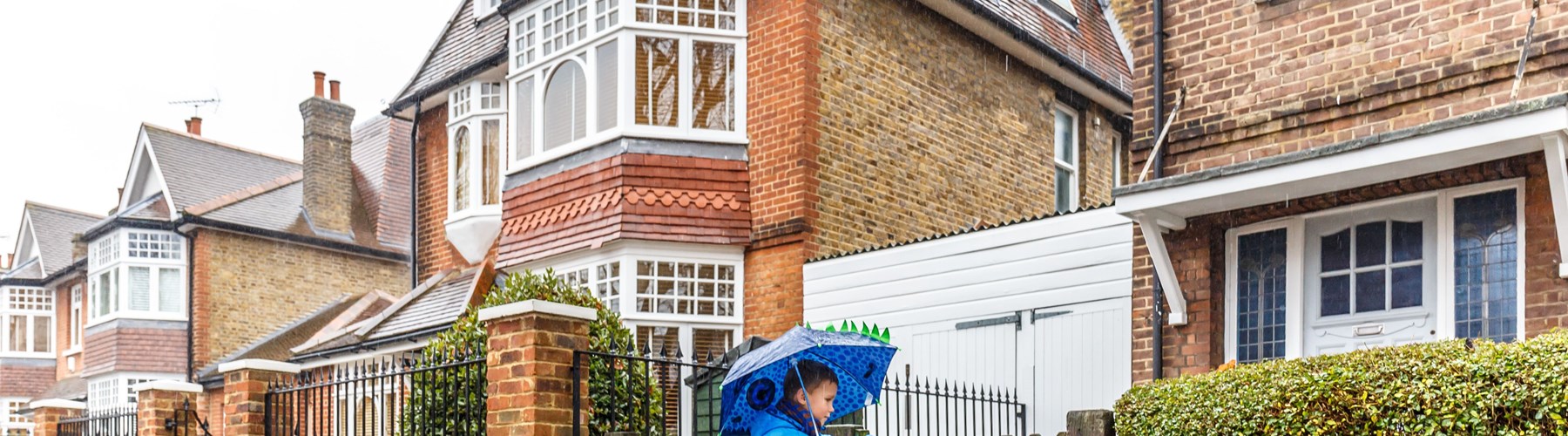 Kid with an umbrella going into his home