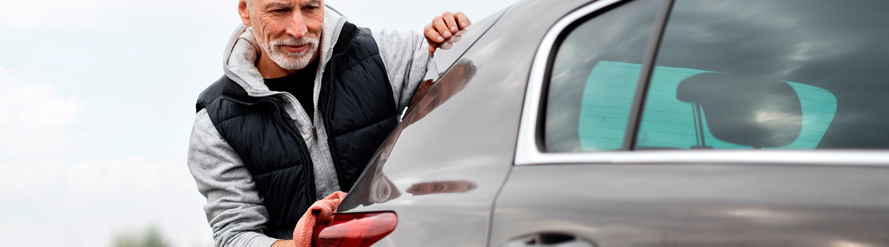 Mature man washing grey car