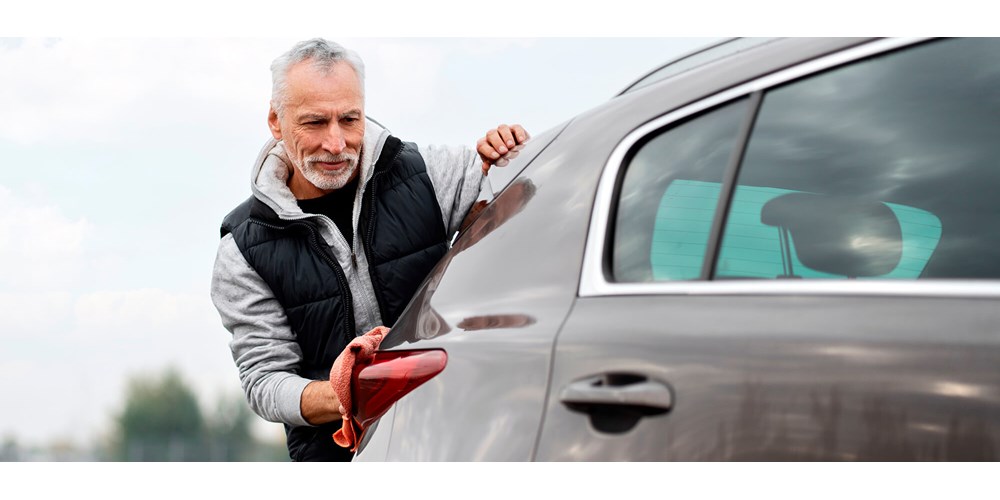 Mature man washing grey car