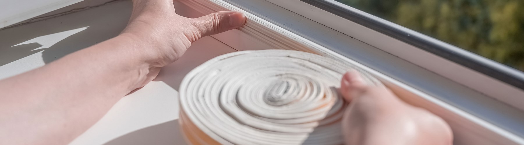 Woman adding insulation strip to windows