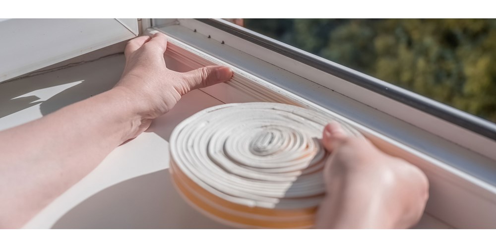 Woman adding insulation strip to windows