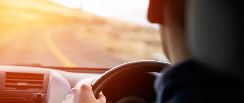 Man driving with sunshine ahead