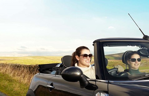 Two young women in a convertible smiling