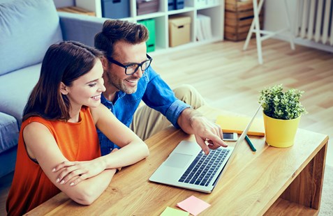 Young woman and man looking at a computer in a living room