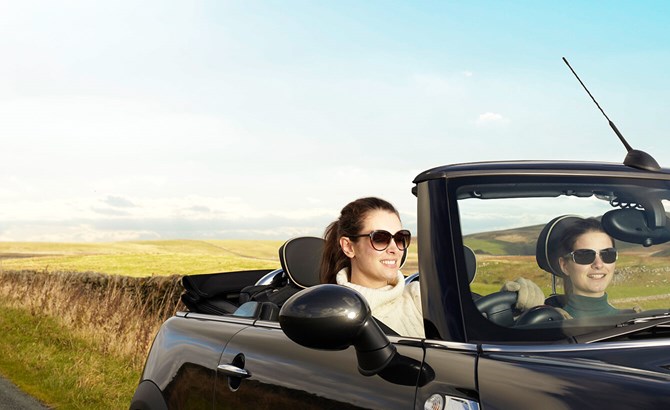 women smiling in convertible car