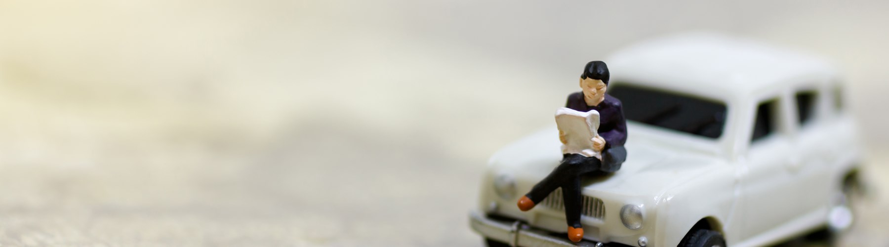 Toy white car and man sitting on bonnet