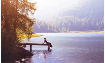 A woman sat at the side of a lake