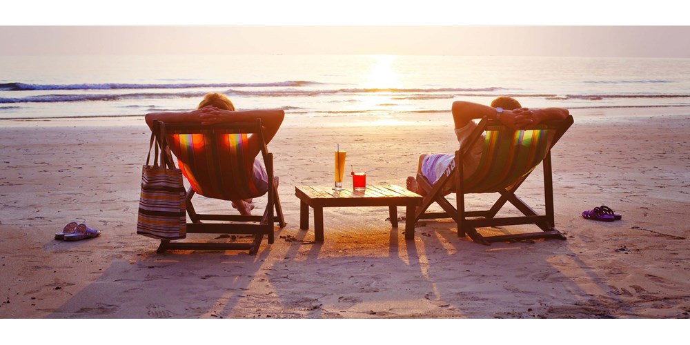 A couple sat on deck chairs on the beach