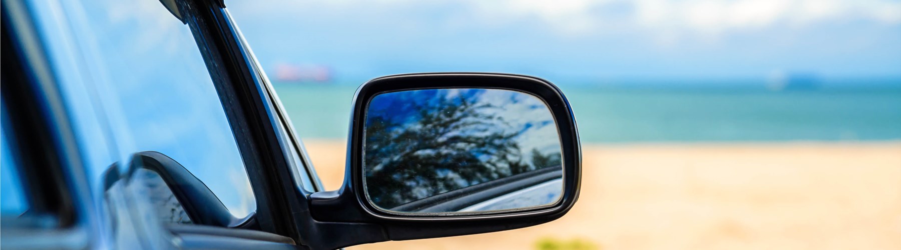 The wing mirror of a car parked at the beach