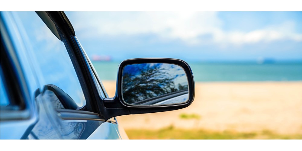 The wing mirror of a car parked at the beach