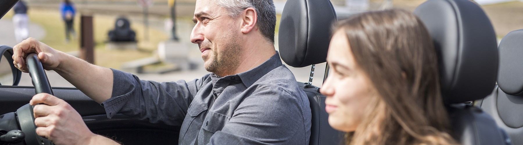 Man in his fifties driving convertible with teenage daughter
