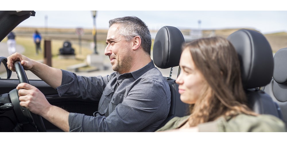 Man in his fifties driving convertible with teenage daughter