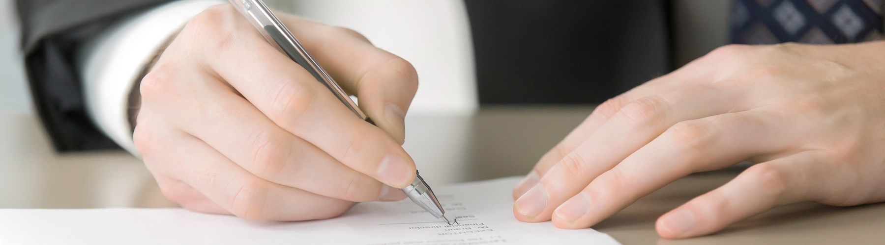 Man in a suit signing document
