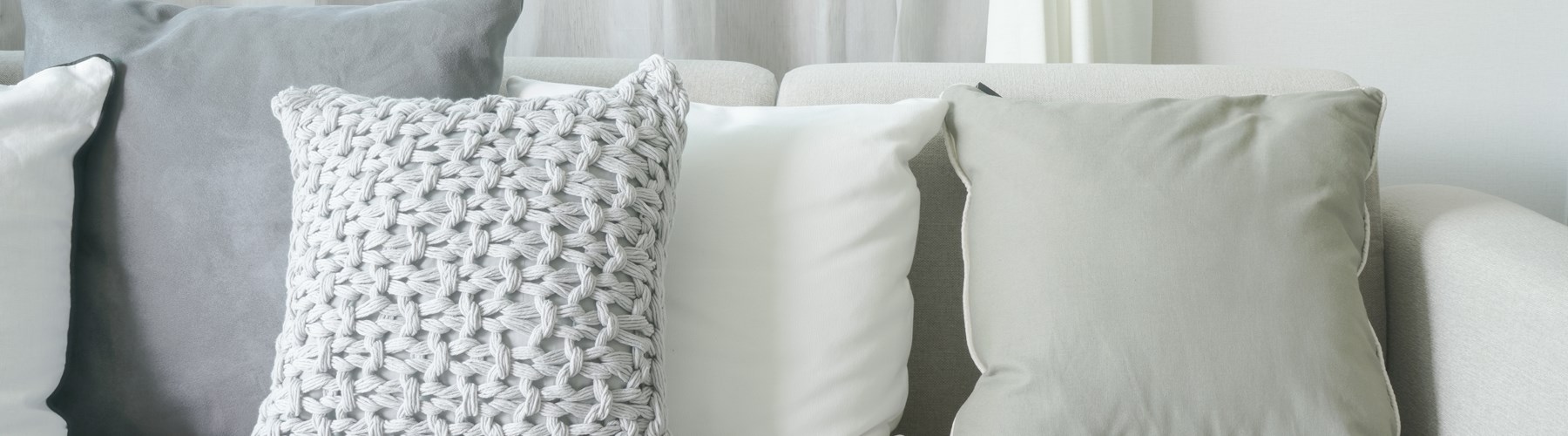 A cream sofa with grey cushions 