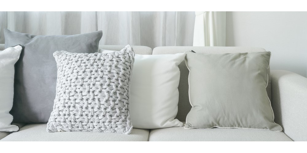 A cream sofa with grey cushions 