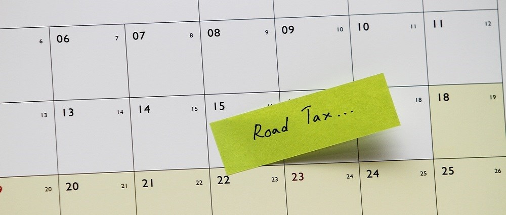 A calendar with a post it note saying "road tax"