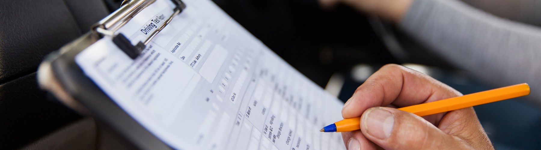 Male hand filling out a driving test form