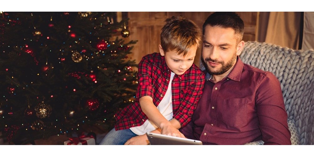 Father and son with tablet by Christmas tree