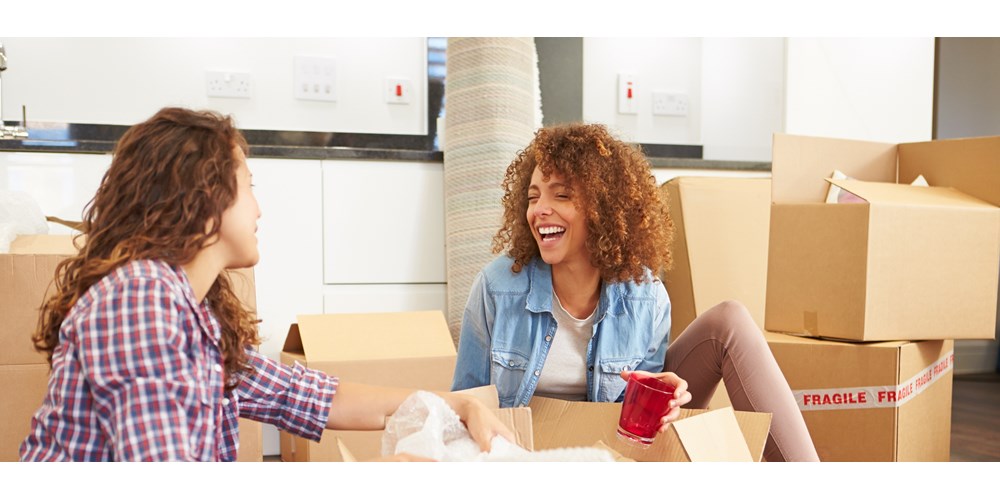 Female friends unpacking and laughing in new home