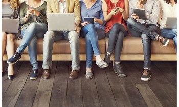 People sat in a row looking at laptops, tablets and phones