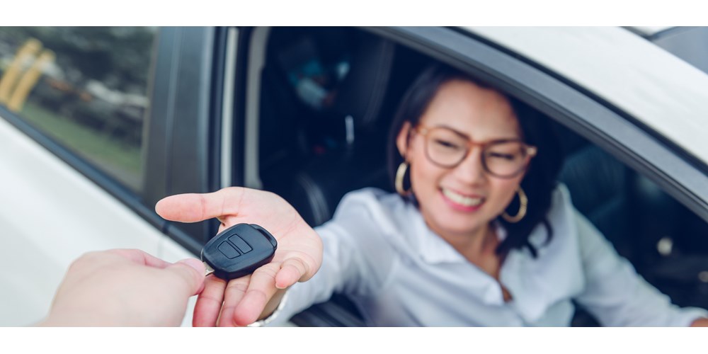 Young woman in car receiving car key