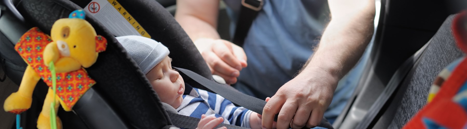 Sleeping baby being fastened in child car seat