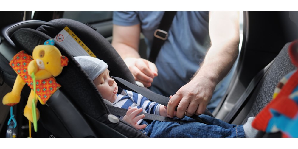 Sleeping baby being fastened in child car seat