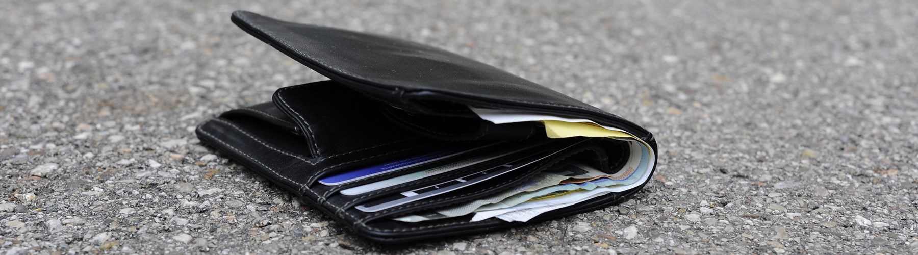 Black leather wallet on gravel floor