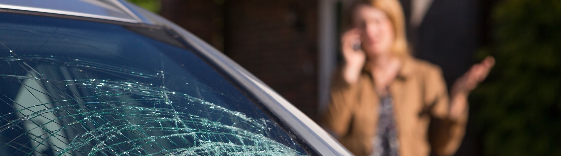 Broken car windscreen and woman on the phone 