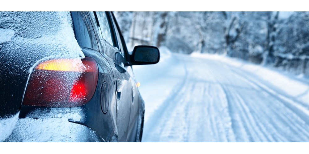 Woman scraping car windscreen on snowy day