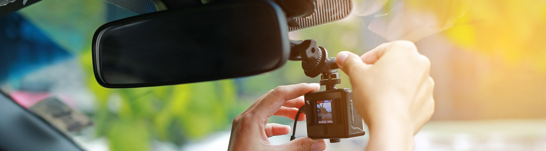 Driver fitting dash cam to car windscreen