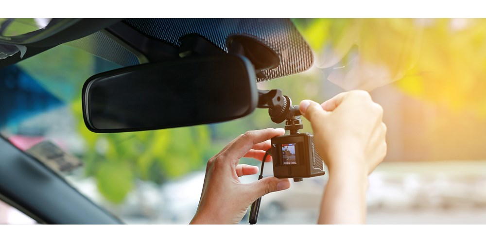 Driver fitting dash cam to car windscreen