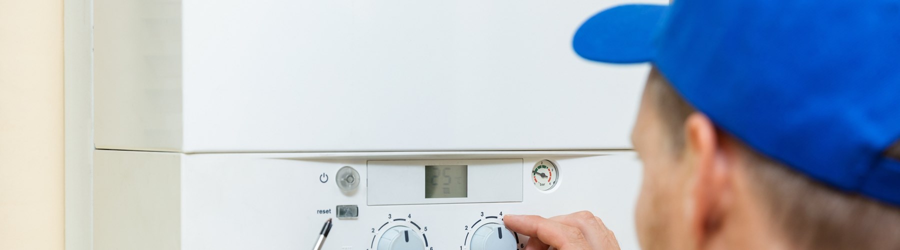 Engineer with blue hat fixing boiler