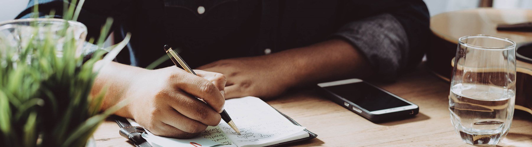 A man sat at a desk writing a list