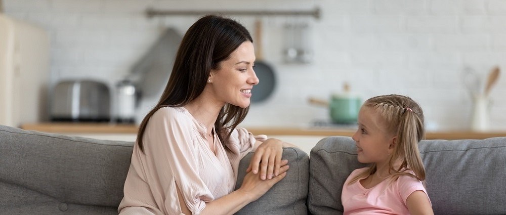 Mother and daughter sitting on sofa