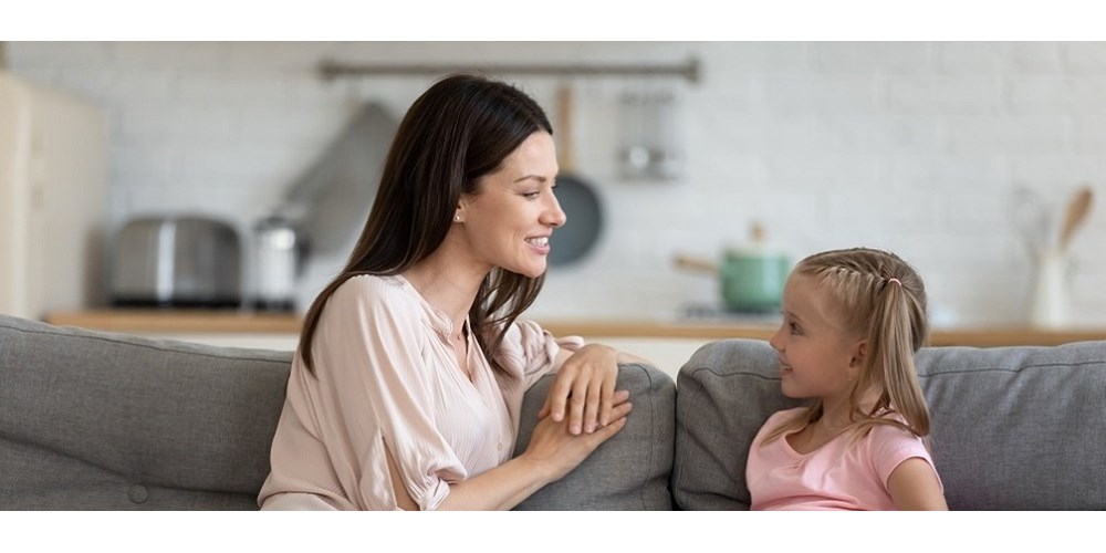 Mother and daughter sitting on sofa