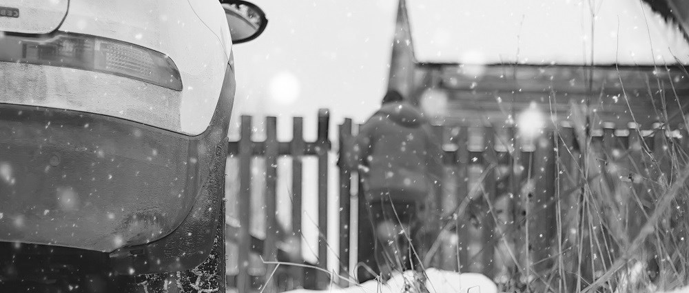 A car parked by a fence in snow