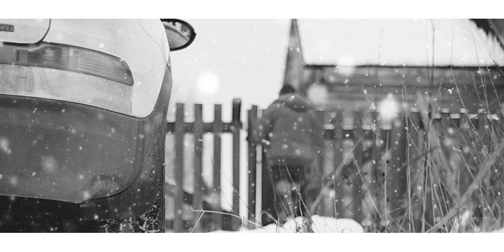 A car parked by a fence in snow