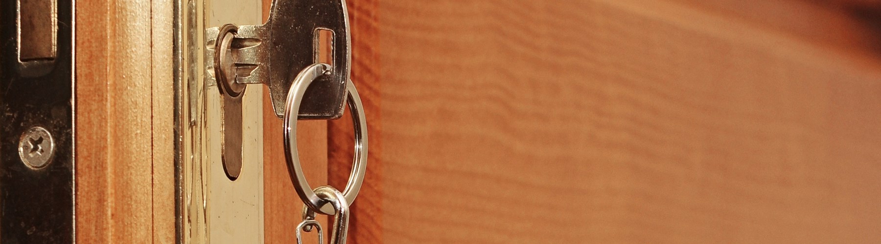 A wooden door being locked with silver key