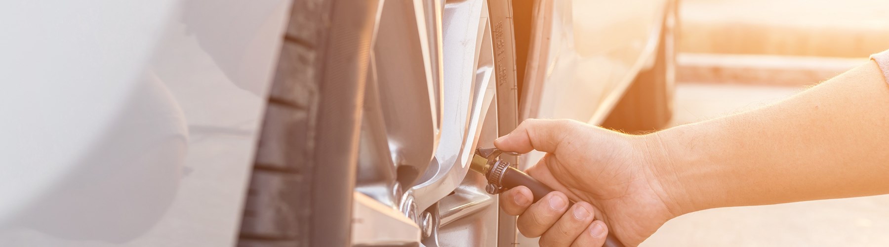 Man checking tyre pressure in silver car