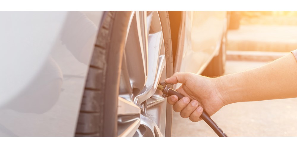 Man checking tyre pressure in silver car