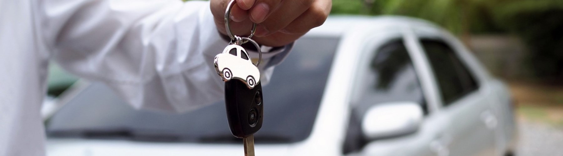 Man handing over car keys in front of silver car