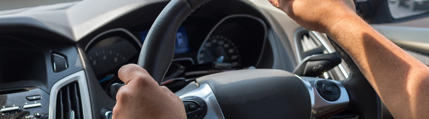 Man's arms on a steering wheel